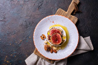 Beyaz peynirli gurme aperatifi ya da koyu beton arka planda taze incir, fındık ve bal içeren camembert peyniri.