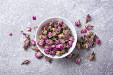 Beyaz kasenin en üst görüntüsü kuru gül tomurcukları ile kokulu çay için gri beton arka planda
