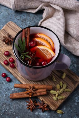 Portakallı, kızılcıklı, tarçınlı, biberiyeli ve mavi beton arkaplanlı diğer malzemelerle sonbahar ya da noel içeceği