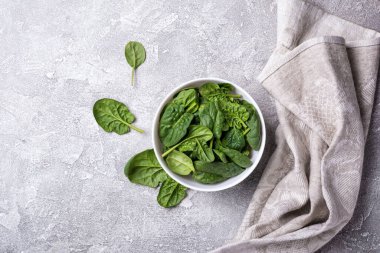 Gri beton arka planda yeşil bebek ıspanağı olan kasenin üst görüntüsü.