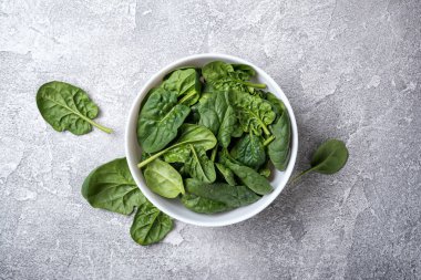 Gri beton arka planda yeşil bebek ıspanağı olan kasenin üst görüntüsü.