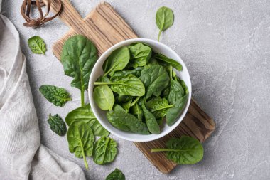 Tahta tahtada yeşil bebek ıspanağı ve gri beton arka planı olan kasenin üst görüntüsü.