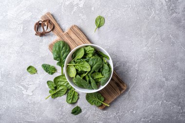 Tahta tahtada yeşil bebek ıspanağı ve gri beton arka planı olan kasenin üst görüntüsü.