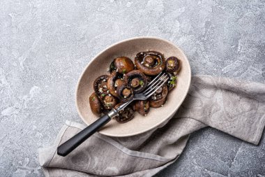 Kavanozda ızgara şampiyon mantarları ve gri beton arka planda baharat.