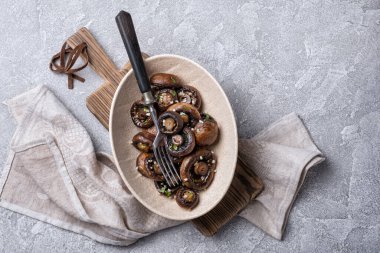 Kavanozda ızgara şampiyon mantarları ve gri beton arka planda baharat.