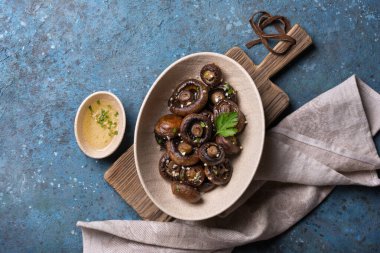 Mavi beton arka planda baharatlı ızgara şampiyon mantarlarının en üst görüntüsü.