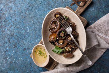 Mavi beton arka planda baharatlı ızgara şampiyon mantarlarının en üst görüntüsü.