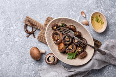 Kavanozda ızgara şampiyon mantarları ve gri beton arka planda baharat.