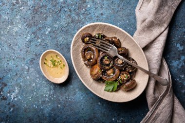 Mavi beton arka planda baharatlı ızgara şampiyon mantarlarının en üst görüntüsü.