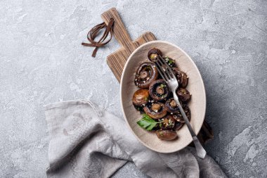 Kavanozda ızgara şampiyon mantarları ve gri beton arka planda baharat.