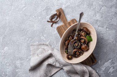Kavanozda ızgara şampiyon mantarları ve gri beton arka planda baharat.