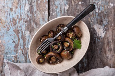 Kavanozda ızgara şampiyon mantarları ve ahşap arka planda baharat.