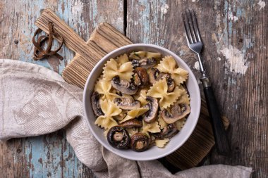 Lezzetli İtalyan farfalle makarnası ve kırsal ahşap arka planda krema soslu şampiyon mantar manzarası.