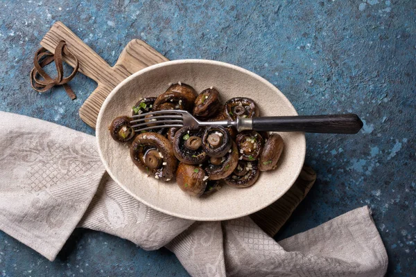 Mavi beton arka planda baharatlı ızgara şampiyon mantarlarının en üst görüntüsü.