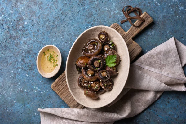 Mavi beton arka planda baharatlı ızgara şampiyon mantarlarının en üst görüntüsü.