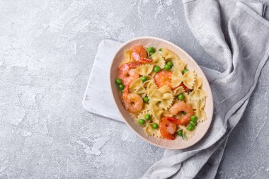 Lezzetli İtalyan farfalle makarnası, karides, karides ve yeşil bezelye, gri beton arka planda.