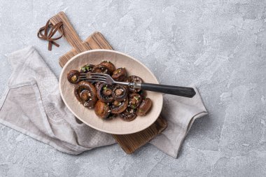 Kavanozda ızgara şampiyon mantarları ve gri beton arka planda baharat.