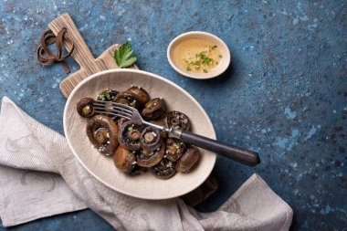 Kavanozda ızgara şampiyon mantarlarının mavi beton arka planda baharatları var.