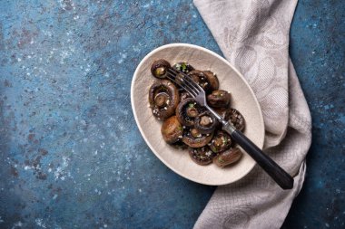 Mavi beton arka planda baharatlı ızgara şampiyon mantarlarının en üst görüntüsü.