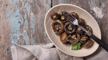 Kavanozda ızgara şampiyon mantarları ve ahşap arka planda baharat.