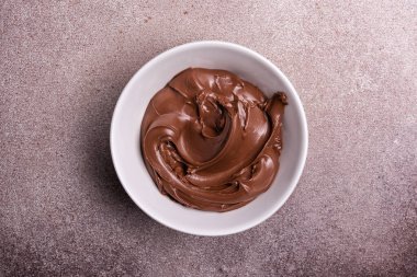 Lezzetli çikolatalı krema ya da kahverengi fındıklı tereyağı, lezzetli ev yapımı tatlı malzemesi olarak, beton arka planda.