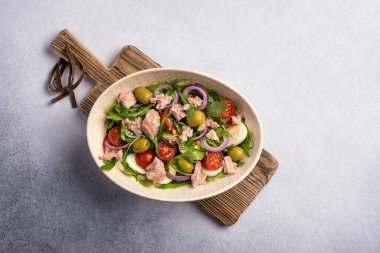 Ton balıklı sağlıklı ve lezzetli salata, taze roka, vişneli domates, bıldırcın yumurtası, soğan ve yeşil zeytinli gri beton zemin