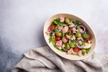 Ton balıklı sağlıklı ve lezzetli salata, taze roka, vişneli domates, bıldırcın yumurtası, soğan ve yeşil zeytinli gri beton zemin