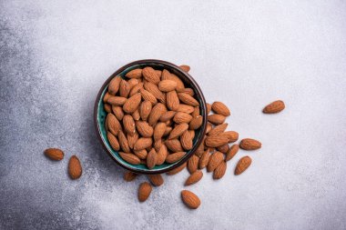 Badem cevizinin en üstteki görüntüsü gri beton arka planda şekerleme malzemesi olarak kasede.