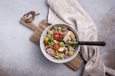 Ton balıklı sağlıklı ve lezzetli salata, taze roka, vişneli domates, bıldırcın yumurtası, soğan ve yeşil zeytinli gri beton zemin