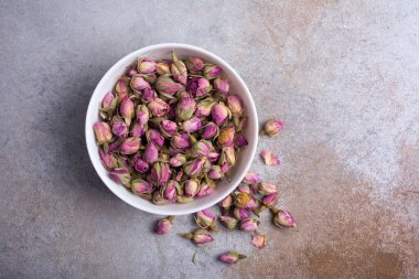 Beyaz kasenin en üst görüntüsü kuru gül tomurcukları ile kokulu çay için gri beton arka planda