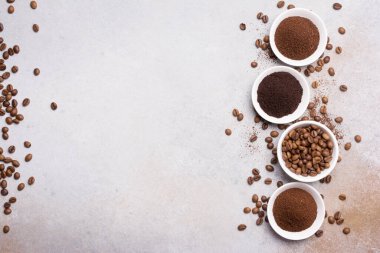 Fotokopi alanı olan gri beton arka planda, beyaz kâselerde öğütülmüş kahve ile kavrulmuş fasulye manzarası.