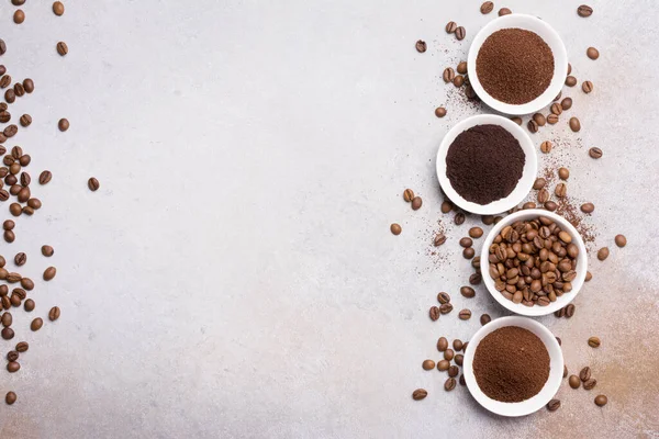 Fotokopi alanı olan gri beton arka planda, beyaz kâselerde öğütülmüş kahve ile kavrulmuş fasulye manzarası.