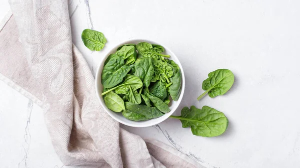 Beyaz mermer arka planda yeşil bebek ıspanağı olan kasenin üst görüntüsü.