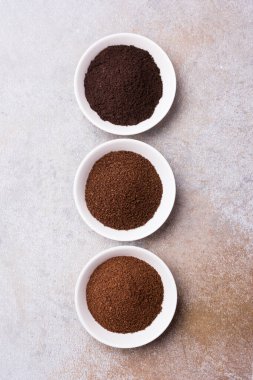 Gri beton arka planda beyaz kâselerde öğütülmüş kahvenin üst görüntüsü