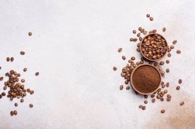 Kavrulmuş fasulye ve fotokopi alanı olan açık gri beton arka planda fincanlarda öğütülmüş kahve.