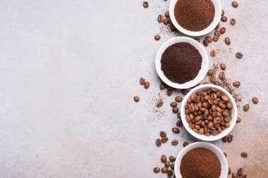 Fotokopi alanı olan gri beton arka planda, beyaz kâselerde öğütülmüş kahve ile kavrulmuş fasulye manzarası.