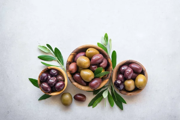 Tasty Olives Wooden Bowls Green Branches Light Background — Foto Stock