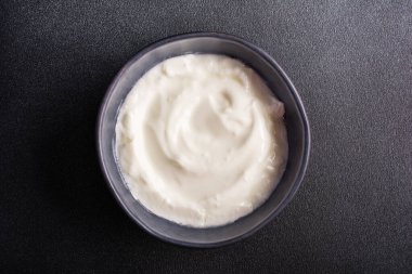 Top view of bowl with healthy dessert or breakfast with yogurt on black concrete background