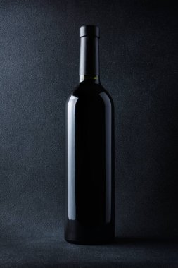 Siyah arka planda bir şişe kırmızı şarap.