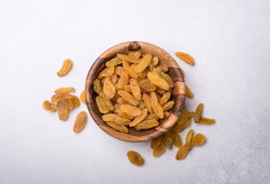 Lezzetli ve sağlıklı yiyecekler için kuru üzümlü ahşap kasenin üst görüntüsü gri beton arka planda.