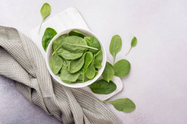 Tahta tahtada yeşil bebek ıspanağı ve gri beton arka planı olan kasenin üst görüntüsü.