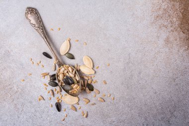 Sağlıklı beslenme için kabak, ayçiçeği ve keten tohumlarının üst görüntüsü kopya alanı olan gri beton arka planda