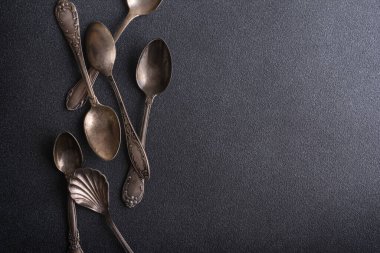 Eskimiş gümüş kaşıkların ya da gümüş çatal bıçakların üst görünümü koyu beton zemin üzerinde kopyalama alanı ile