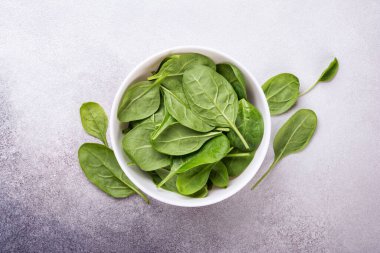 Gri beton arka planda yeşil bebek ıspanağı olan kasenin üst görüntüsü.