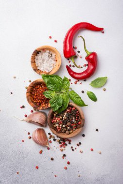 Biberli, tuzlu, sarımsaklı, fesleğenli ve kırmızı acı biberli biberli, gri beton arka planda baharatlı ve aromatik yiyeceklerin üst görüntüsü.