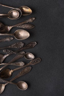 Eskimiş gümüş kaşıkların ya da koyu beton arka plandaki gümüş çatal bıçakların üst görünümü