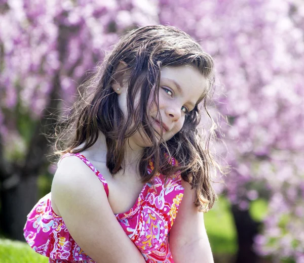 Petite fille timide assise dans un jardin — Photo