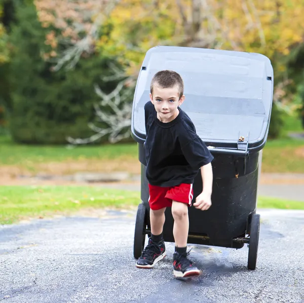 Young boy bringing trash can up the driveway Royalty Free Stock Photos