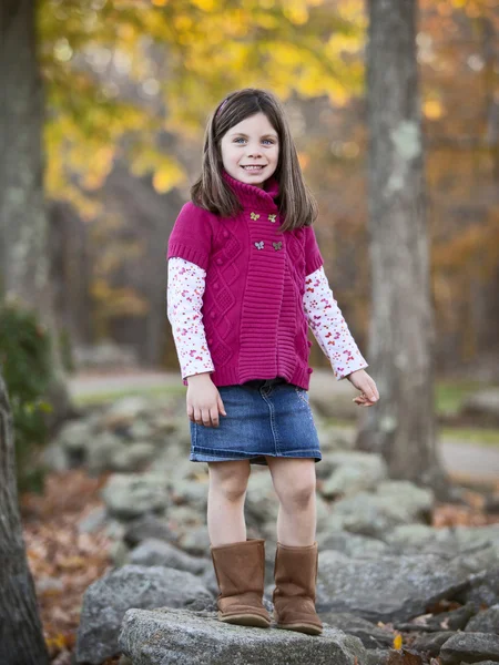 Pretty girl portrait in the park climbing on rocks — Stock Photo, Image