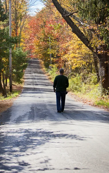 Mann läuft an einem schönen Herbsttag die Straße entlang — Stockfoto